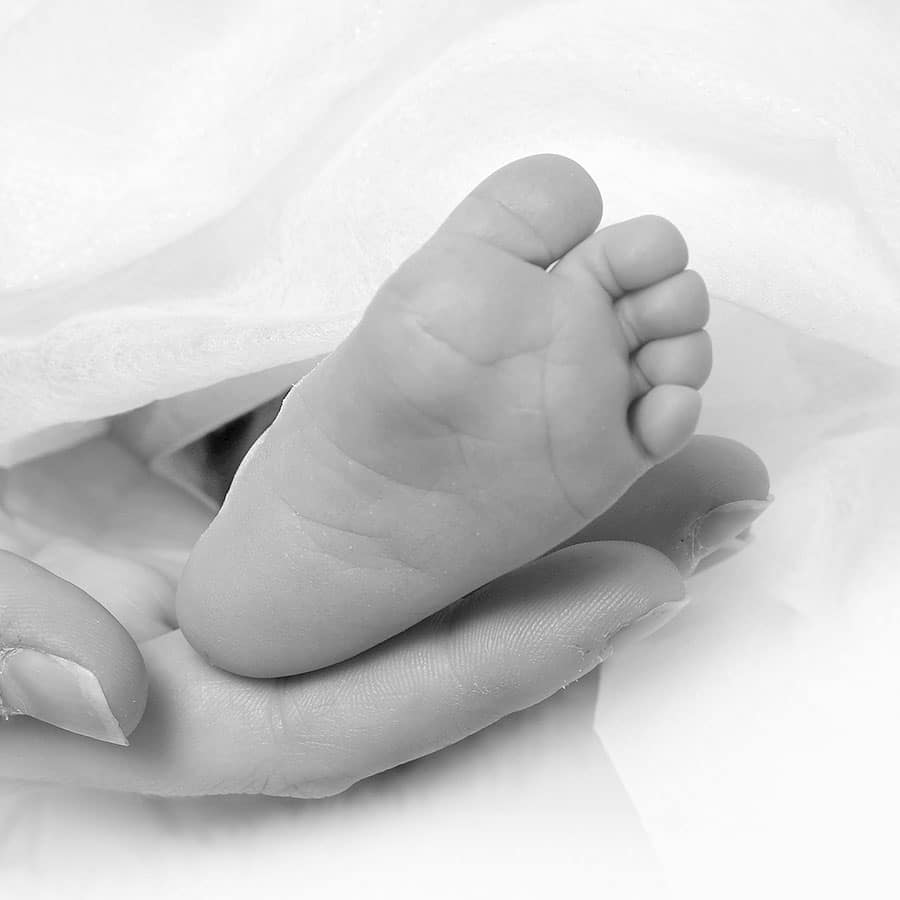 Babyfuß in der Hand eines Erwachsenen